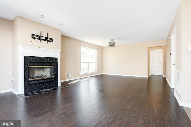 unfurnished living room featuring a high end fireplace, visible vents, dark wood-type flooring, and baseboards