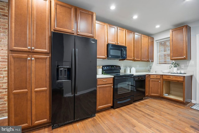 kitchen with recessed lighting, black appliances, light wood-style flooring, and light countertops