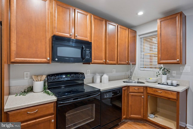 kitchen with brown cabinetry, recessed lighting, a sink, black appliances, and light countertops