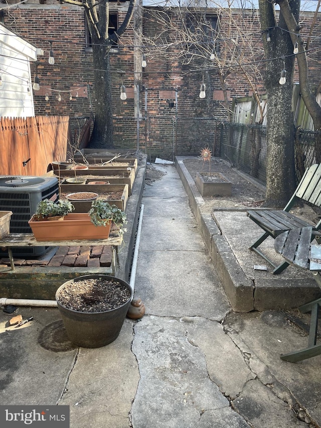 view of patio with cooling unit, a vegetable garden, and fence