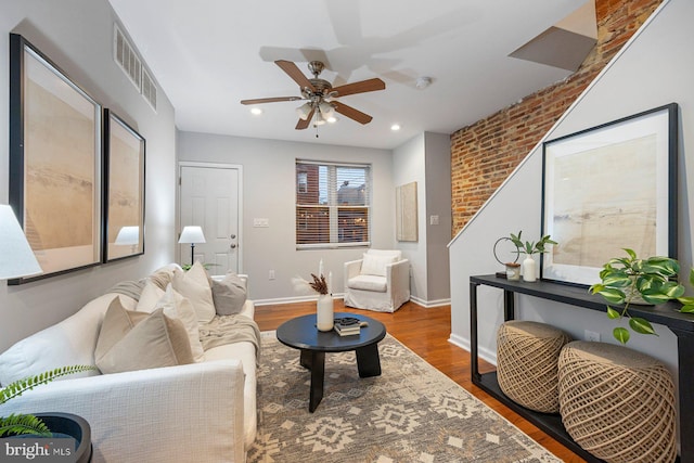 living area featuring visible vents, baseboards, a ceiling fan, and wood finished floors