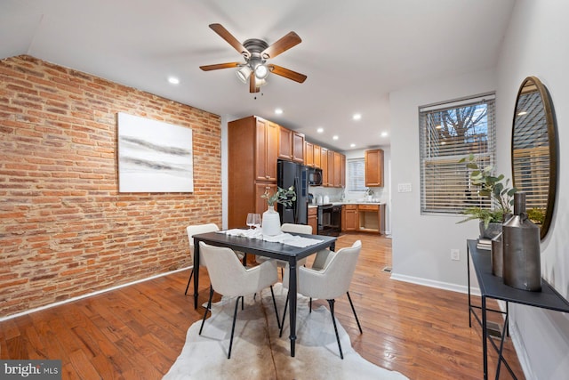 dining space featuring a ceiling fan, recessed lighting, brick wall, light wood finished floors, and baseboards