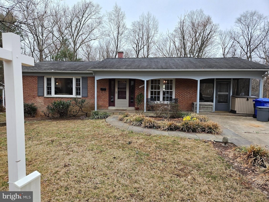 single story home featuring a front yard, covered porch, brick siding, and a chimney