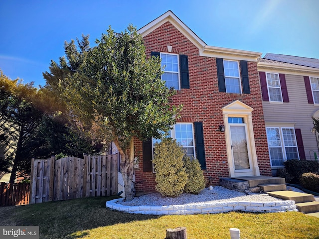 view of front of house with a front lawn, fence, and brick siding