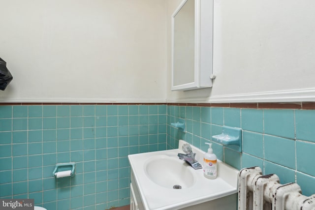 bathroom featuring wainscoting, radiator, vanity, and tile walls
