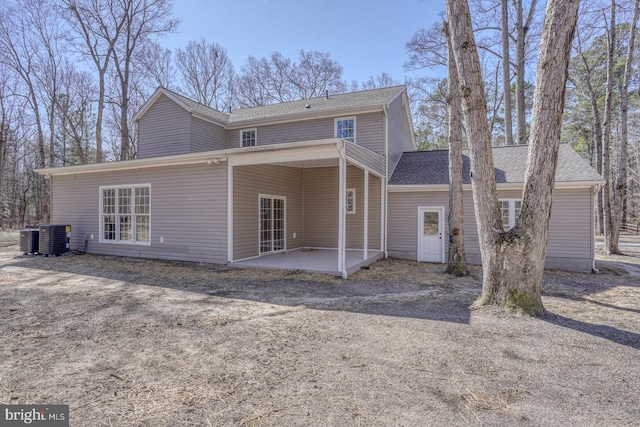 rear view of property featuring cooling unit, a patio area, and roof with shingles