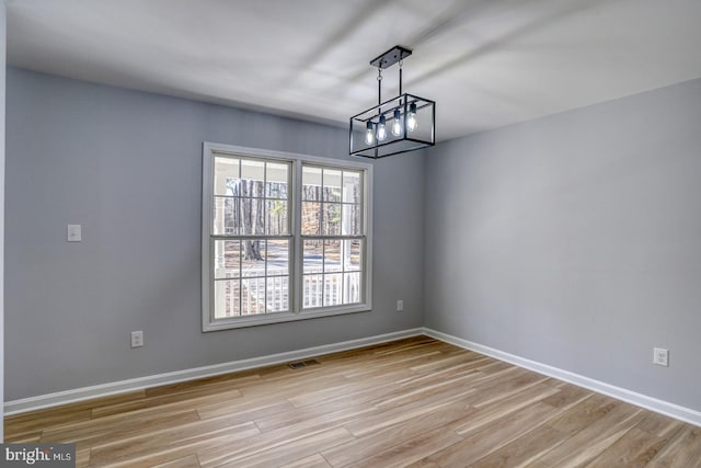 unfurnished dining area featuring light wood finished floors, visible vents, and baseboards