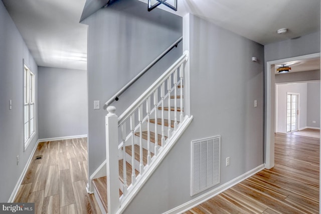 staircase with visible vents, baseboards, and wood finished floors