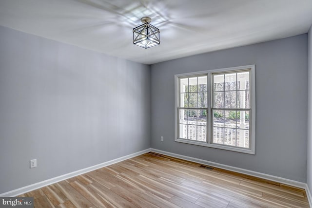 spare room with visible vents, wood finished floors, and baseboards