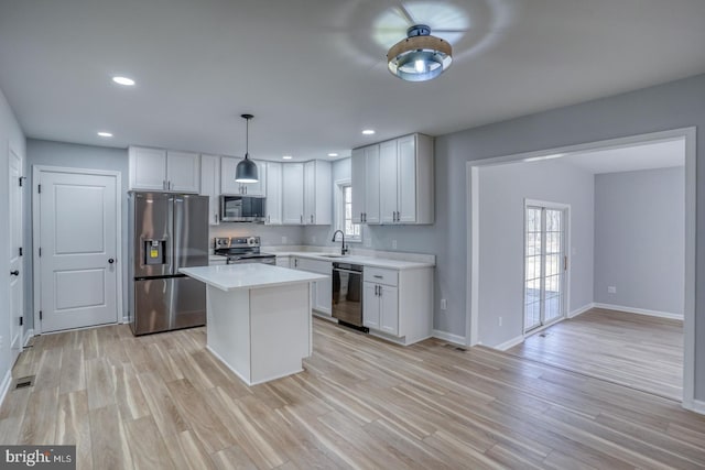 kitchen featuring light wood finished floors, stainless steel appliances, light countertops, and a wealth of natural light