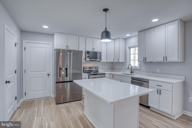 kitchen featuring light wood-style flooring, a sink, stainless steel appliances, white cabinets, and light countertops