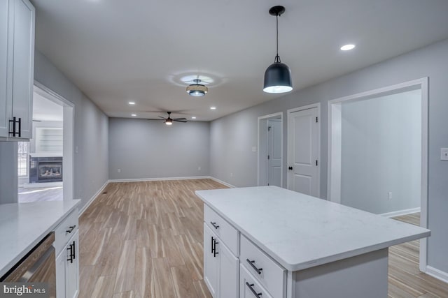 kitchen with a glass covered fireplace, white cabinets, dishwasher, and light wood-style flooring