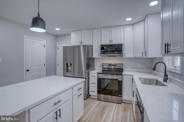 kitchen featuring light stone countertops, light wood-style flooring, a sink, stainless steel appliances, and white cabinetry