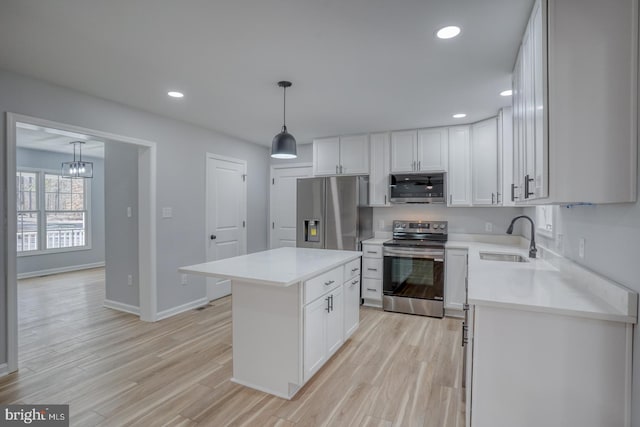 kitchen featuring recessed lighting, a sink, stainless steel appliances, light countertops, and light wood-type flooring