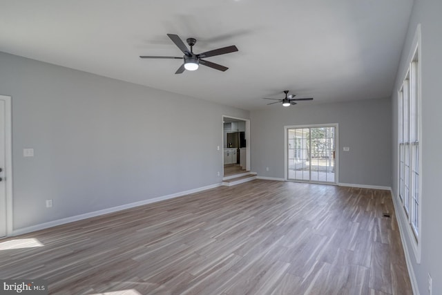 unfurnished living room featuring ceiling fan, baseboards, and wood finished floors