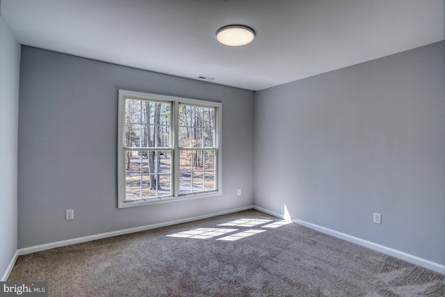 carpeted spare room with visible vents and baseboards