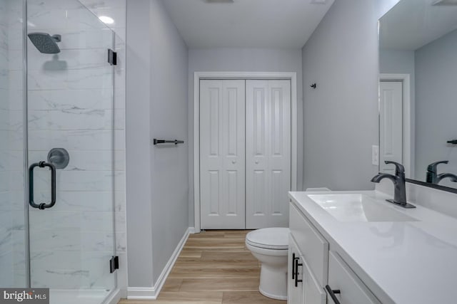 bathroom with vanity, wood finished floors, baseboards, a stall shower, and toilet