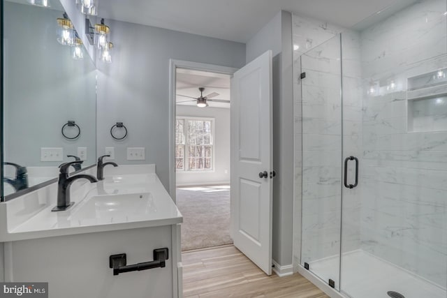 full bathroom with a shower stall, wood finished floors, double vanity, and a sink