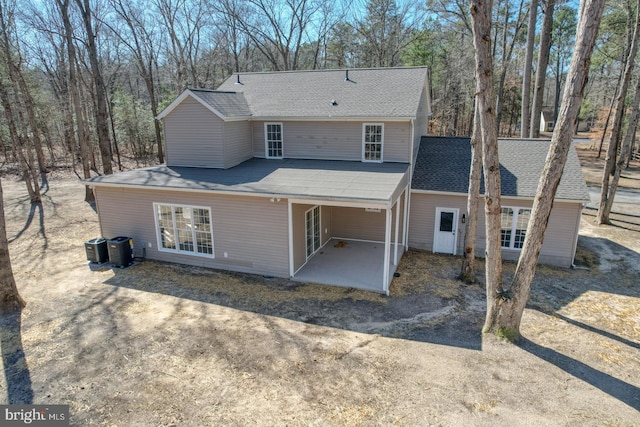 rear view of house featuring a patio area, central AC unit, driveway, and a shingled roof