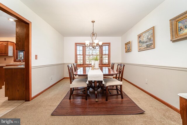 dining area with baseboards, light carpet, and a chandelier