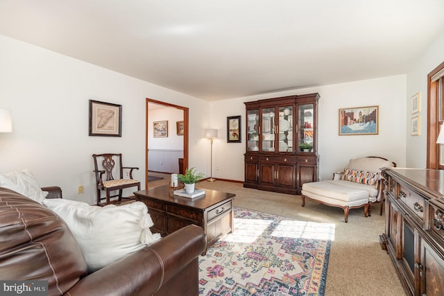 living area with baseboards and light colored carpet