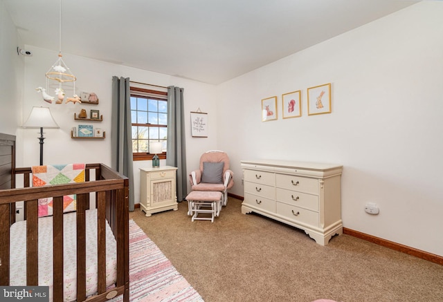 bedroom with baseboards, a crib, and carpet flooring