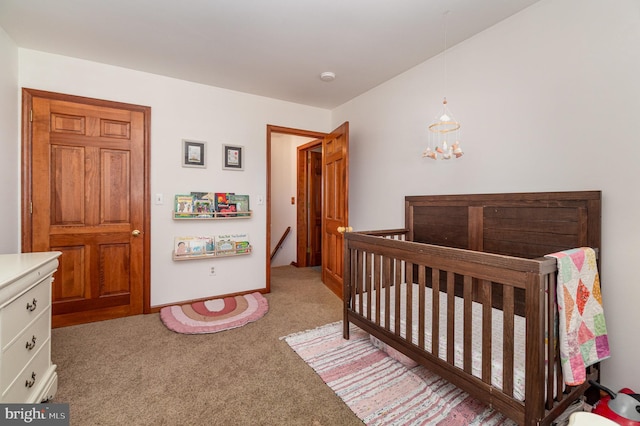 bedroom with light carpet, a nursery area, and an inviting chandelier