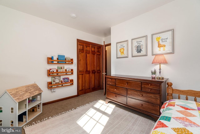 carpeted bedroom with a closet and baseboards