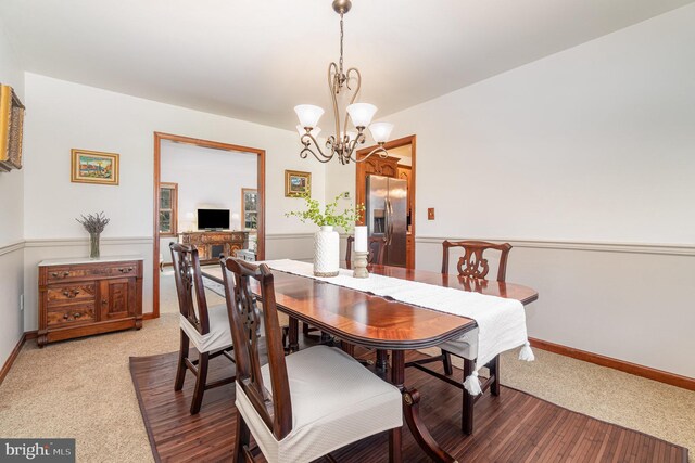 dining room with light colored carpet, wainscoting, and a chandelier