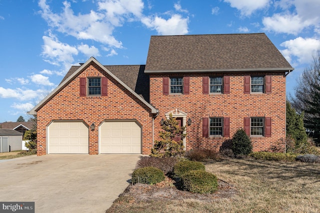 colonial home with concrete driveway, an attached garage, brick siding, and roof with shingles