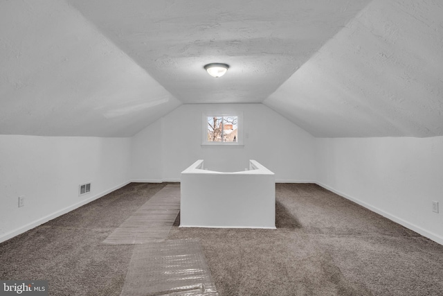 additional living space with visible vents, carpet flooring, a textured ceiling, and baseboards