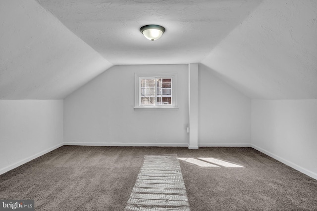 additional living space featuring baseboards, carpet floors, a textured ceiling, and vaulted ceiling