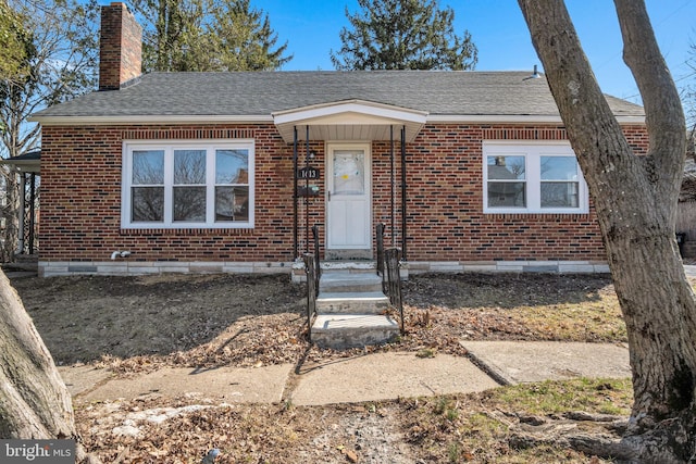 view of front of house featuring brick siding, a chimney, and a shingled roof