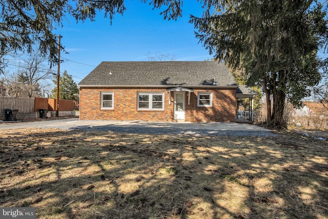 view of front of property with brick siding, a shingled roof, and fence