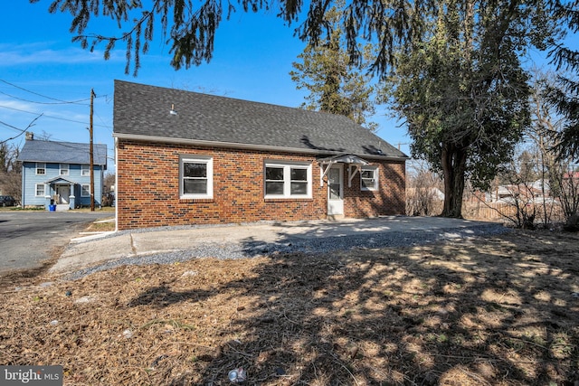 view of side of home featuring brick siding and roof with shingles