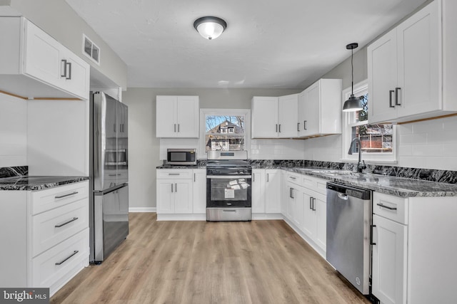 kitchen with visible vents, decorative backsplash, stainless steel appliances, white cabinetry, and a sink