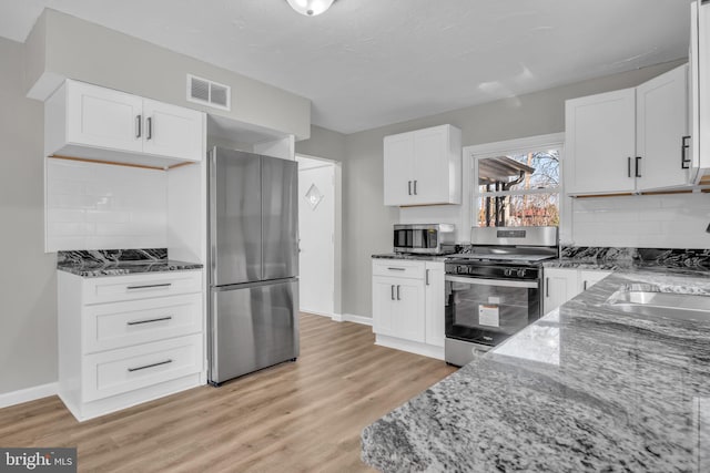 kitchen featuring light stone counters, visible vents, appliances with stainless steel finishes, and light wood finished floors