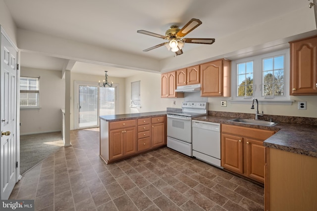 kitchen with white appliances, a peninsula, a sink, under cabinet range hood, and dark countertops