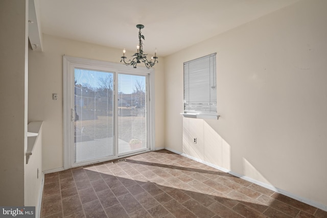 unfurnished dining area featuring baseboards and a chandelier