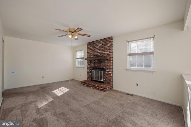 unfurnished living room featuring visible vents, a brick fireplace, ceiling fan, baseboards, and carpet