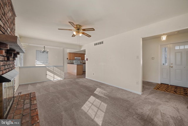 unfurnished living room featuring visible vents, ceiling fan with notable chandelier, baseboards, and light carpet