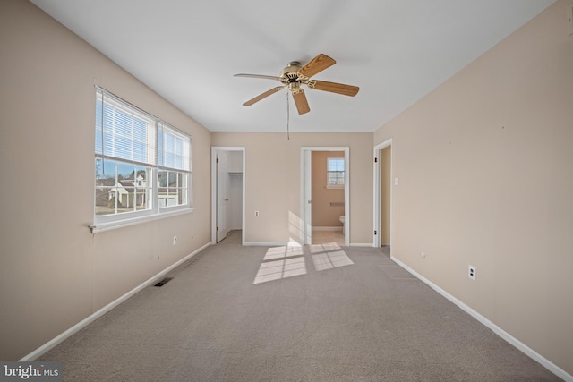 unfurnished bedroom featuring visible vents, a walk in closet, baseboards, carpet floors, and ensuite bathroom