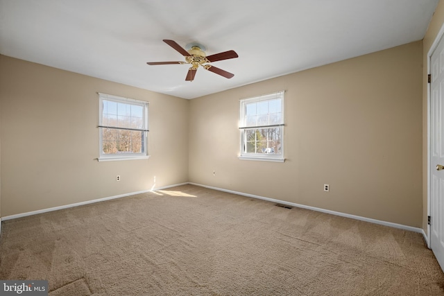 carpeted empty room with visible vents, plenty of natural light, and baseboards