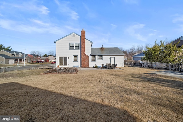 rear view of house featuring a fenced backyard, a patio, a chimney, and a yard