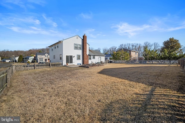 exterior space with a lawn, a fenced backyard, and a chimney