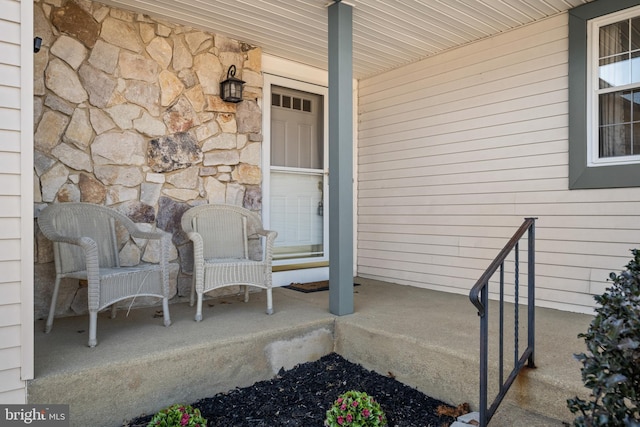 property entrance featuring stone siding and covered porch