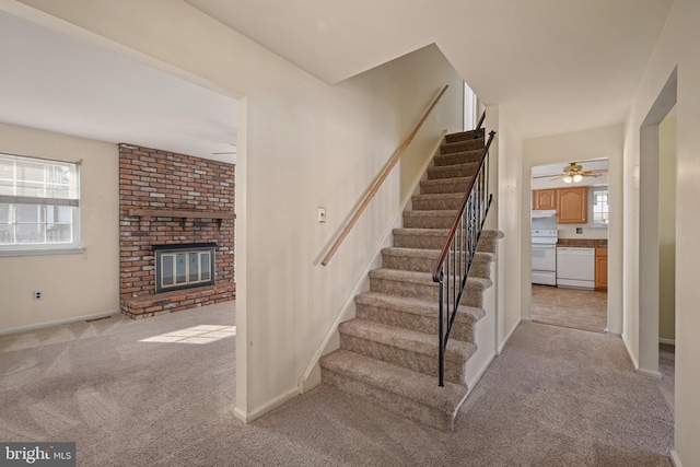 stairs featuring carpet flooring, a fireplace, baseboards, and ceiling fan