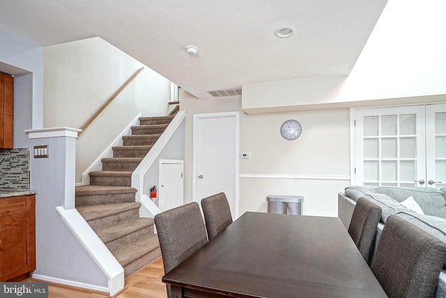 dining space with visible vents, light wood-style flooring, and stairway