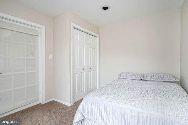 carpeted bedroom featuring a closet and baseboards