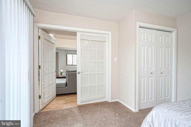 bedroom featuring a closet, baseboards, light colored carpet, and french doors